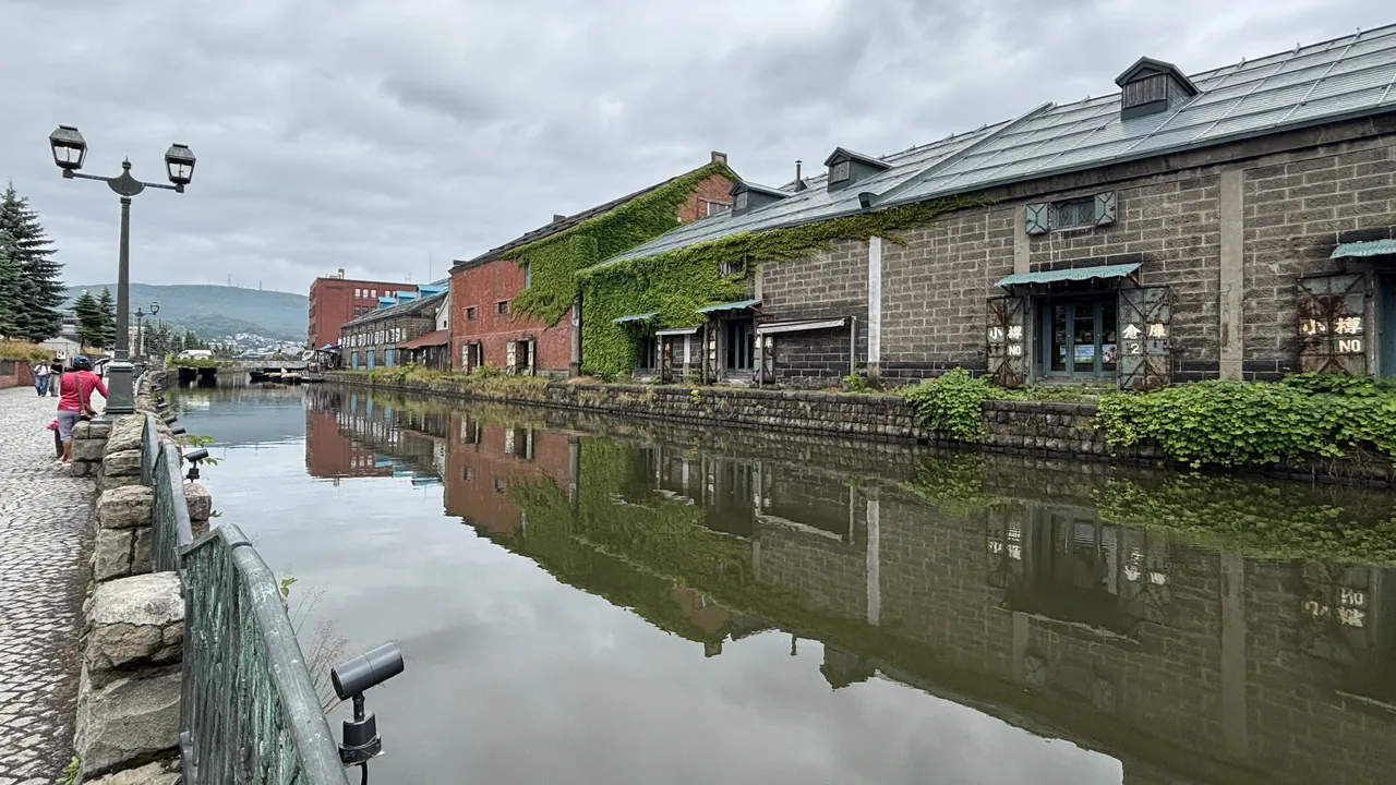Historic brick and stone warehouses line a water canal with visible reflections under an overcast sky.